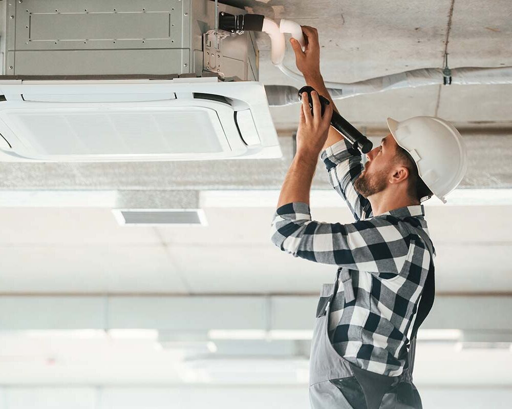 Technitian repairs office air conditioner